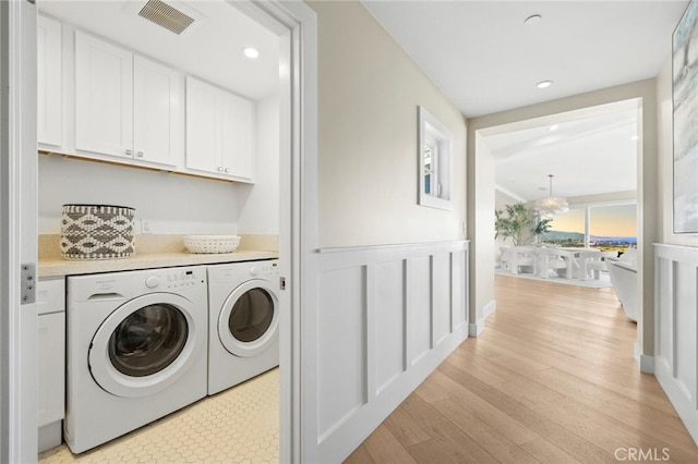washroom featuring visible vents, recessed lighting, washer and clothes dryer, cabinet space, and light wood finished floors