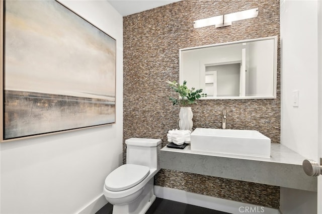 bathroom featuring a sink, decorative backsplash, and toilet