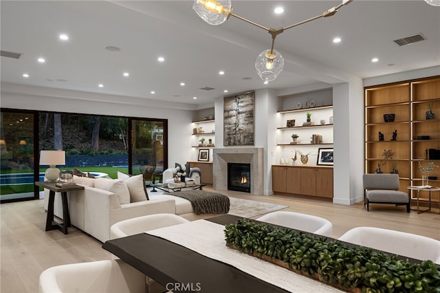 living area with visible vents, recessed lighting, a glass covered fireplace, and light wood-type flooring