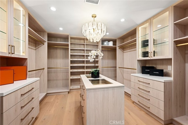 walk in closet featuring a notable chandelier, visible vents, and light wood-type flooring