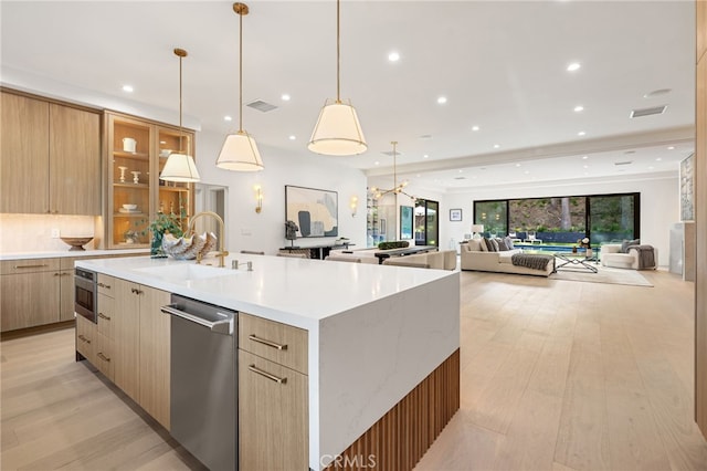 kitchen featuring stainless steel dishwasher, light wood-style floors, modern cabinets, a large island with sink, and a sink