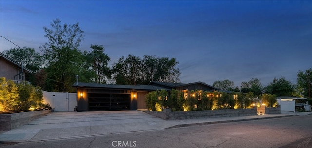 modern home with concrete driveway, an attached garage, fence, and a gate