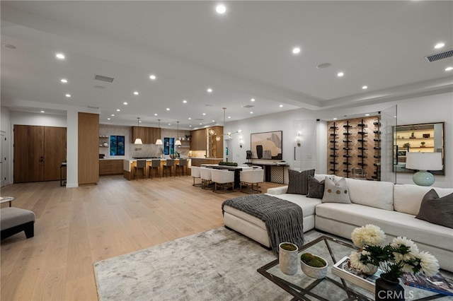 living area featuring light wood-style floors, recessed lighting, and visible vents