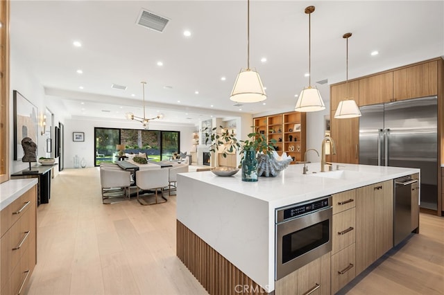 kitchen with a sink, stainless steel microwave, open floor plan, visible vents, and modern cabinets