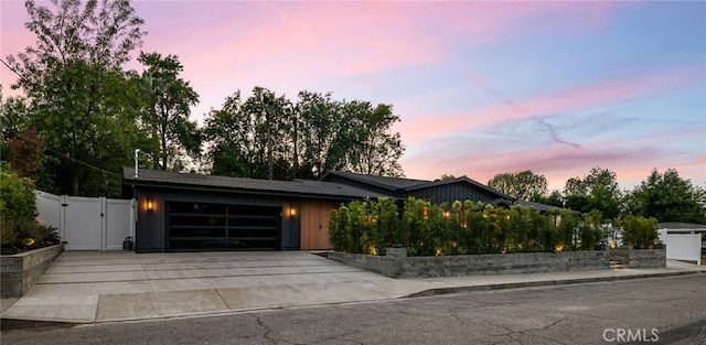 contemporary home featuring board and batten siding, a gate, fence, concrete driveway, and an attached garage