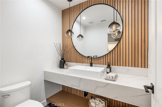 half bath featuring toilet, visible vents, and vanity