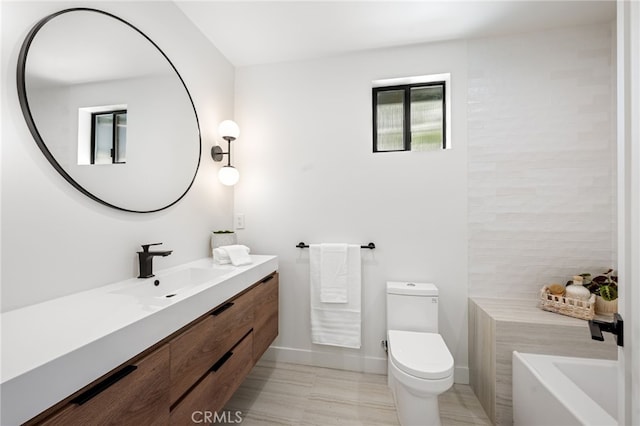 full bath featuring toilet, a washtub, baseboards, and vanity
