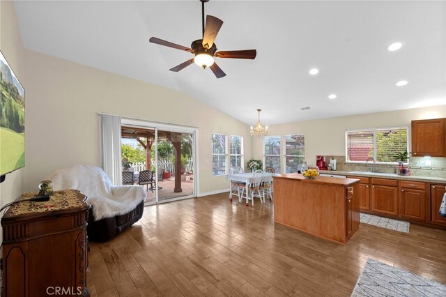 kitchen featuring lofted ceiling, a kitchen island, light wood-style floors, light countertops, and a sink