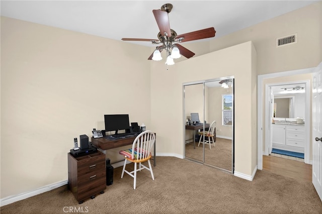 carpeted home office with a ceiling fan, baseboards, and visible vents