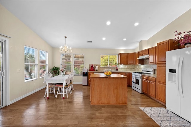 kitchen featuring a center island, light wood finished floors, a notable chandelier, lofted ceiling, and white appliances
