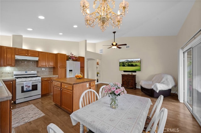 dining area with visible vents, wood finished floors, high vaulted ceiling, ceiling fan with notable chandelier, and recessed lighting