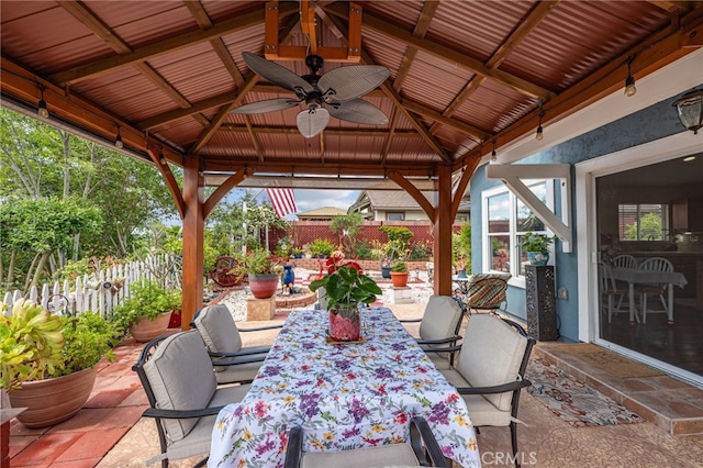 view of patio with outdoor dining area, ceiling fan, fence, and a gazebo