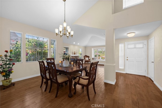dining space featuring baseboards, vaulted ceiling, a notable chandelier, and hardwood / wood-style flooring