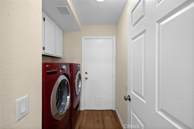 laundry room with cabinet space, baseboards, wood finished floors, visible vents, and washer and clothes dryer
