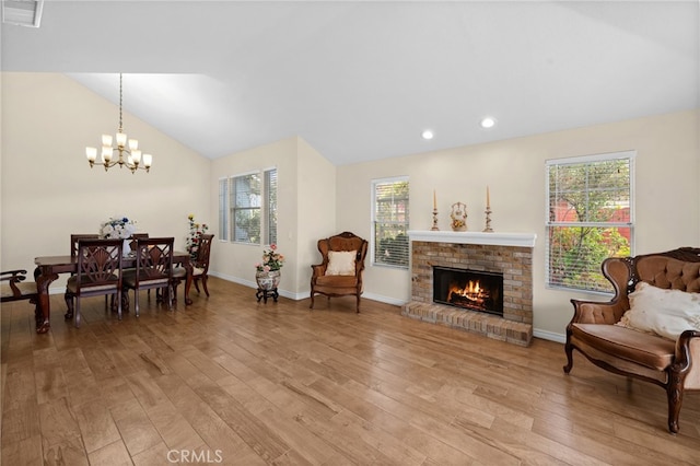 interior space featuring a fireplace, light wood-style floors, a chandelier, lofted ceiling, and visible vents
