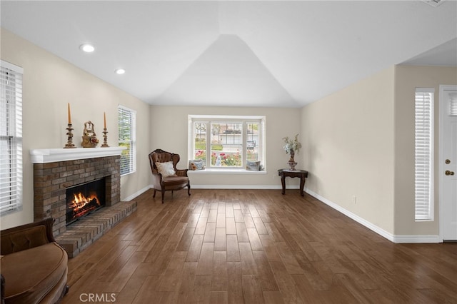 sitting room with baseboards, vaulted ceiling, wood finished floors, and a fireplace