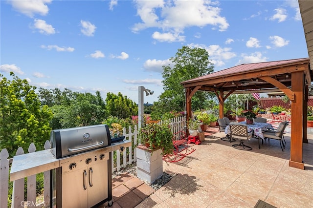 view of patio featuring fence, outdoor dining area, and a gazebo