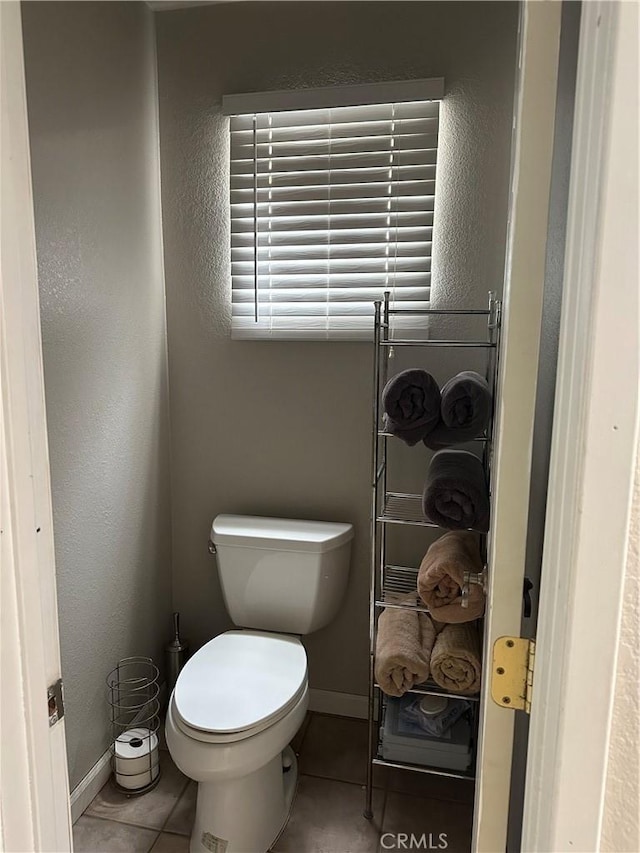 bathroom with toilet, tile patterned floors, and baseboards