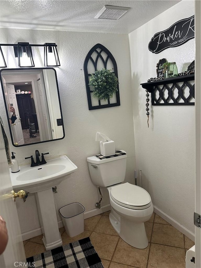 bathroom featuring a textured ceiling, visible vents, tile patterned flooring, baseboards, and toilet