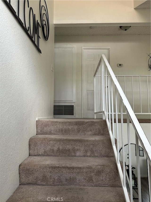 stairs with visible vents and a textured wall