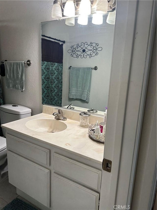 full bathroom with vanity, a textured wall, and toilet