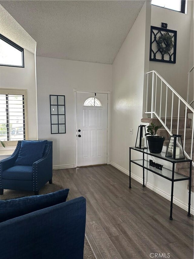 entryway with a textured ceiling, vaulted ceiling, wood finished floors, baseboards, and stairs