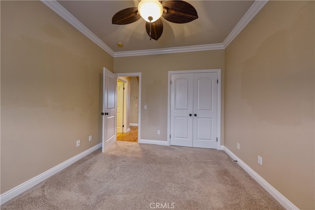 unfurnished bedroom with baseboards, light carpet, ornamental molding, and a closet