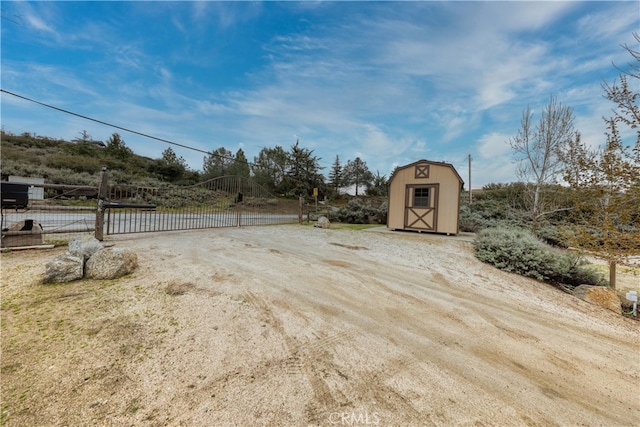 exterior space with fence, a gate, an outbuilding, and a shed