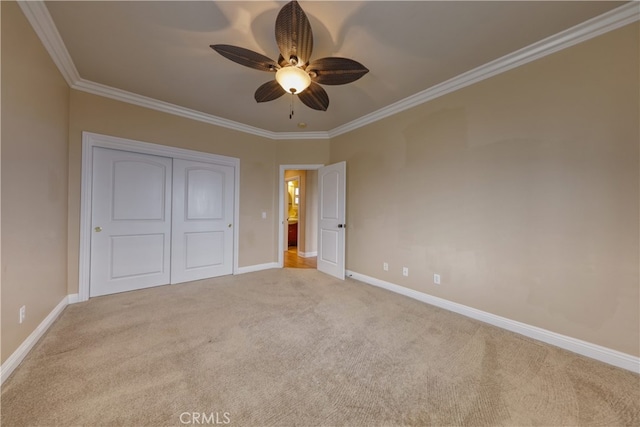 unfurnished bedroom with baseboards, ornamental molding, carpet, and a closet