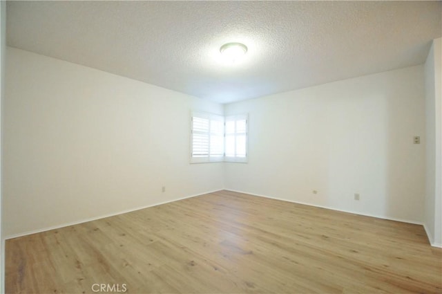 spare room with light wood-type flooring and a textured ceiling