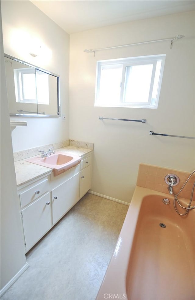 bathroom with vanity, baseboards, and a bath