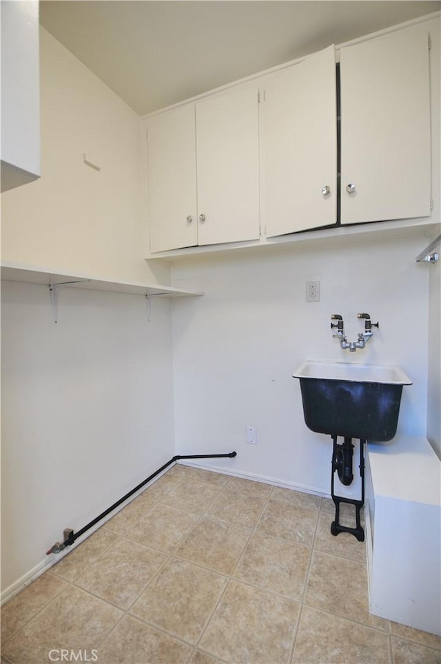 laundry room with baseboards, laundry area, a sink, and light tile patterned flooring