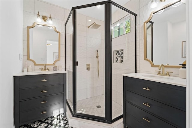full bath with a sink, a stall shower, and two vanities