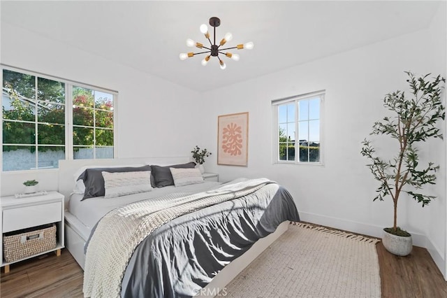 bedroom with baseboards, an inviting chandelier, and wood finished floors