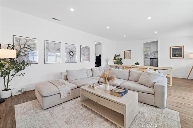 living room with recessed lighting, baseboards, visible vents, and light wood-style floors