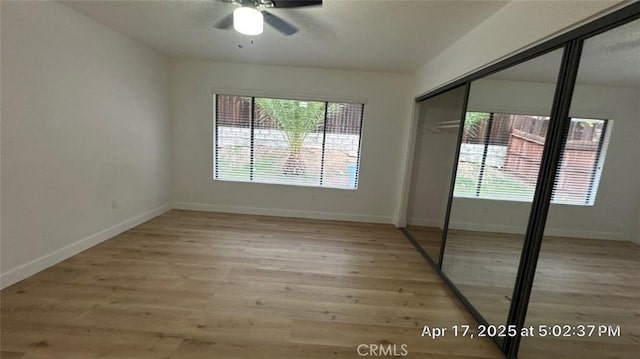 unfurnished bedroom featuring a ceiling fan, baseboards, wood finished floors, and a closet