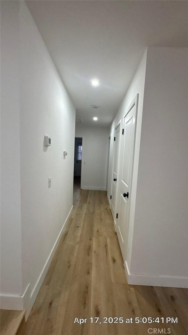 hallway featuring light wood-type flooring, recessed lighting, and baseboards