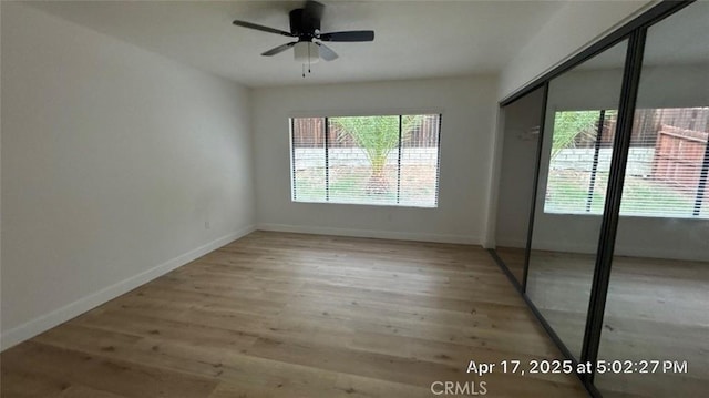 empty room with baseboards, ceiling fan, and wood finished floors