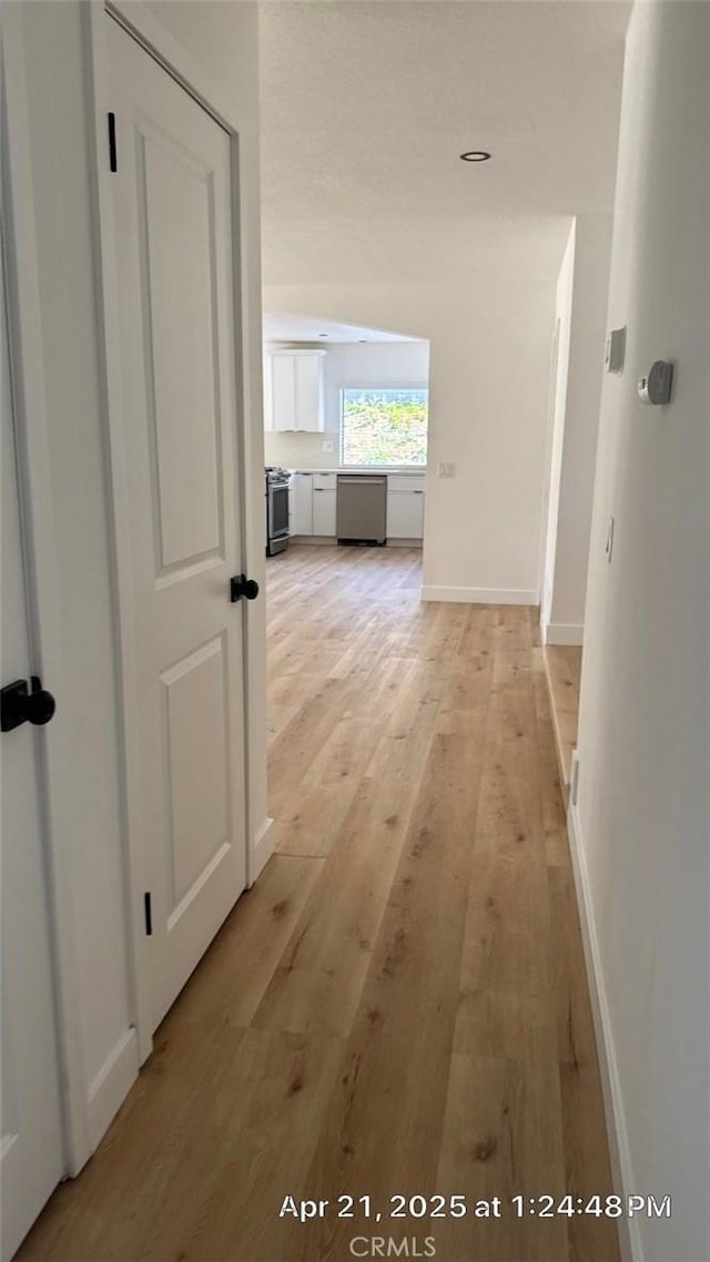 hall with baseboards and light wood-style flooring
