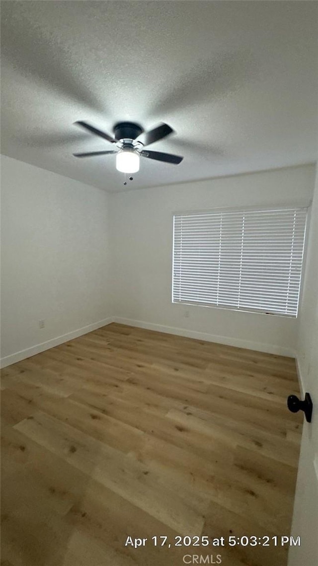 empty room featuring baseboards, ceiling fan, a textured ceiling, and wood finished floors