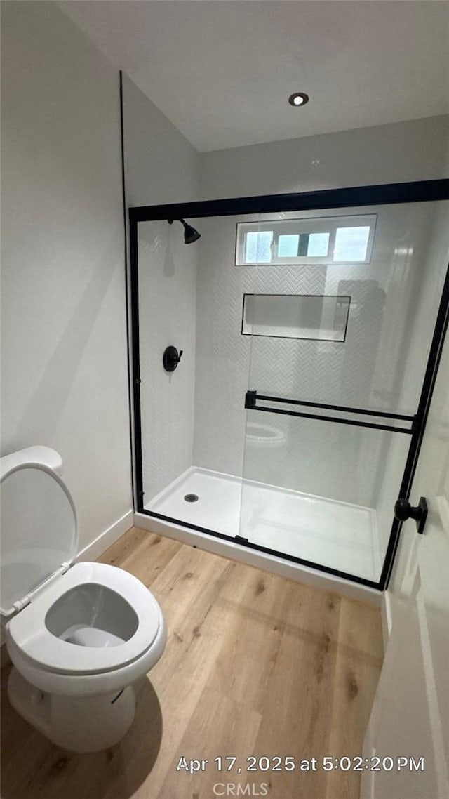 full bathroom featuring toilet, baseboards, a shower stall, and wood finished floors