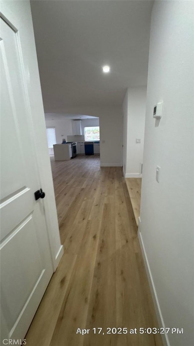 corridor featuring light wood-type flooring, recessed lighting, and baseboards