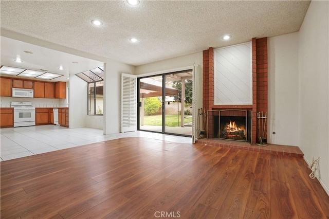 unfurnished living room with recessed lighting, a textured ceiling, light wood-style flooring, and a fireplace