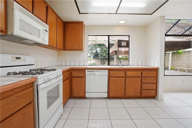 kitchen featuring white appliances, tile countertops, brown cabinets, and light tile patterned flooring