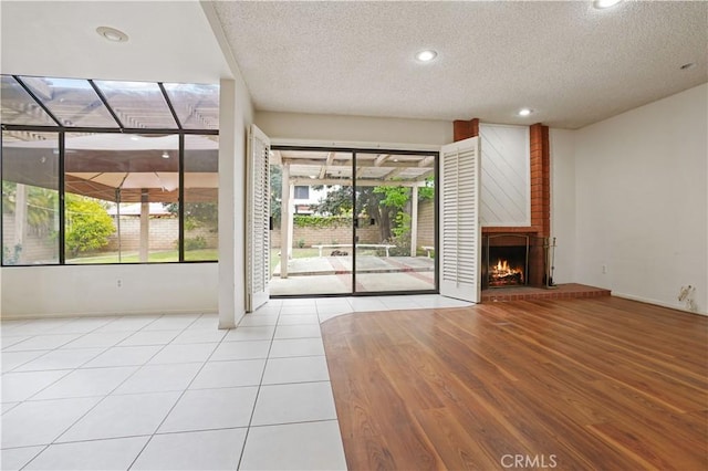 unfurnished living room with recessed lighting, a textured ceiling, tile patterned floors, and a fireplace
