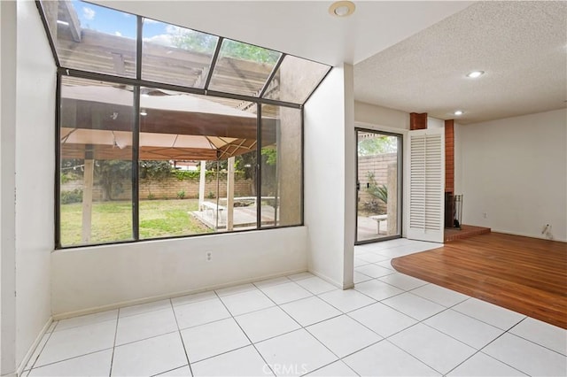 tiled empty room with baseboards, a fireplace with raised hearth, and a textured ceiling