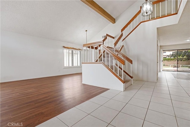 stairs featuring a textured ceiling, wood finished floors, high vaulted ceiling, beamed ceiling, and a notable chandelier