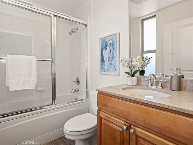 bathroom with vanity, shower / bath combination with glass door, and toilet