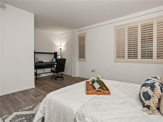 bedroom featuring baseboards, wood finished floors, and visible vents