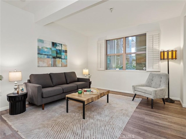 living room with baseboards, beamed ceiling, and wood finished floors